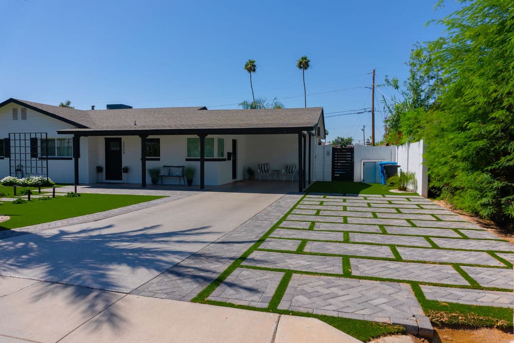 Modern single-story home with a landscaped driveway and green lawn under a clear blue sky.