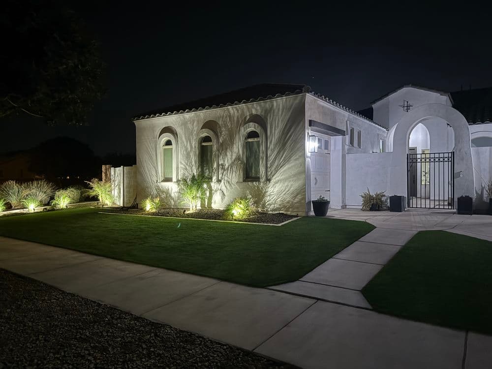 Modern white house with elegant landscaping and soft night lighting, creating a welcoming ambiance.