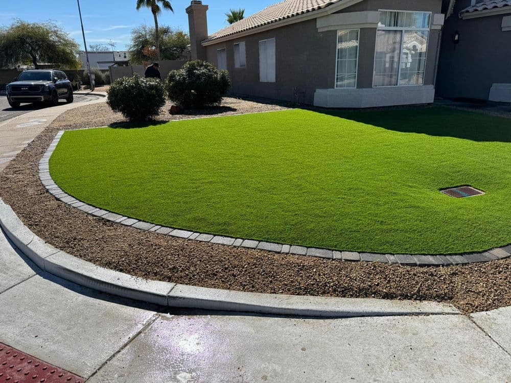 Lush green artificial lawn with decorative gravel and landscaping in a residential front yard.