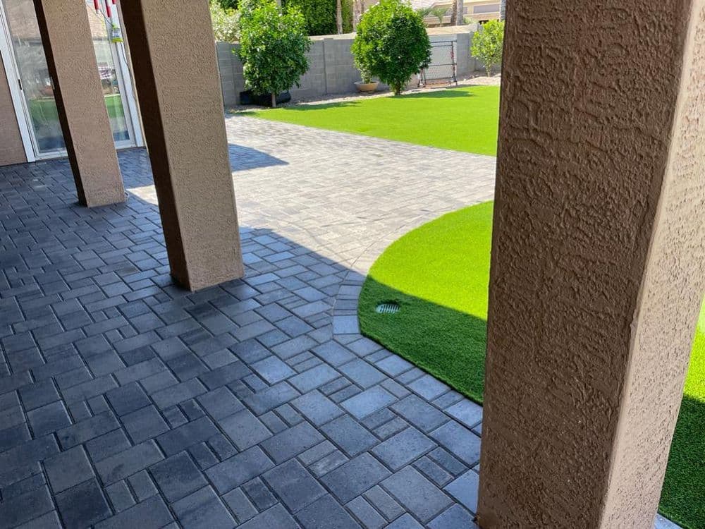Paved patio with curved lawn and greenery, showcasing modern outdoor design.