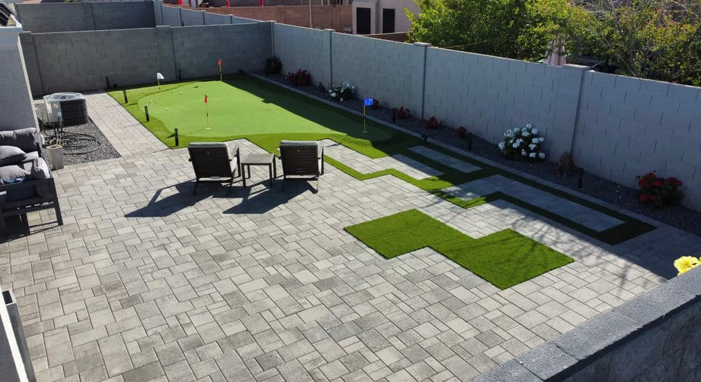 Modern backyard with patio, putting green, and lounge chairs surrounded by planters.