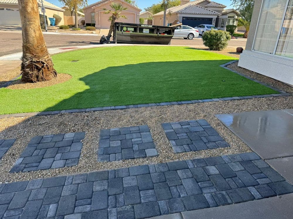 Artificial grass lawn with stone pathway and desert landscaping in residential neighborhood.