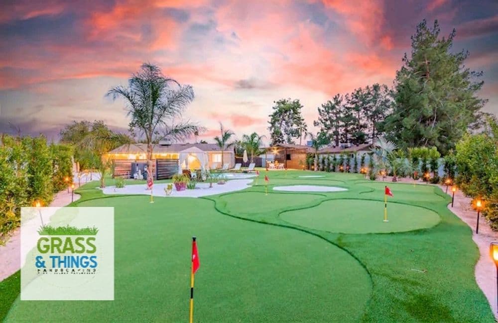 Lush mini golf course with vibrant greens and palm trees under a sunset sky. Grass & Things logo.